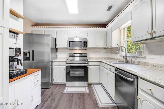 kitchen with decorative backsplash, stainless steel appliances, sink, dark hardwood / wood-style floors, and white cabinetry