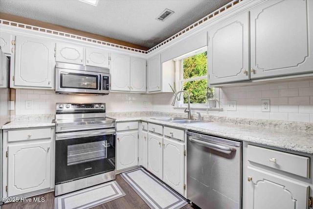 kitchen featuring backsplash, dark hardwood / wood-style flooring, stainless steel appliances, sink, and white cabinetry