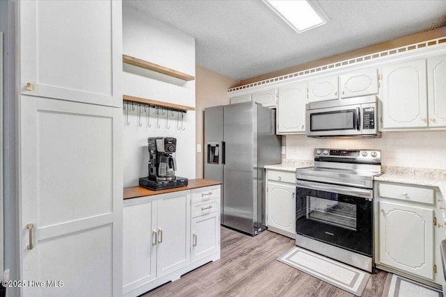 kitchen with light hardwood / wood-style flooring, backsplash, a textured ceiling, white cabinets, and appliances with stainless steel finishes