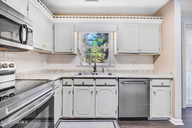 kitchen with sink, dark hardwood / wood-style flooring, decorative backsplash, white cabinets, and appliances with stainless steel finishes