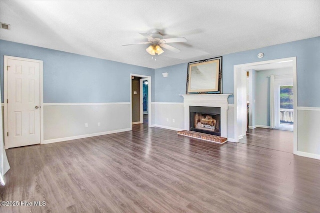 unfurnished living room with ceiling fan, dark hardwood / wood-style flooring, and a textured ceiling