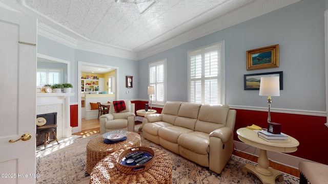 living room featuring hardwood / wood-style floors, ornamental molding, and a brick fireplace