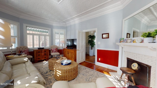 living room with hardwood / wood-style flooring, a brick fireplace, and ornamental molding