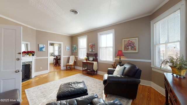 living room with crown molding, plenty of natural light, a premium fireplace, and light wood-type flooring