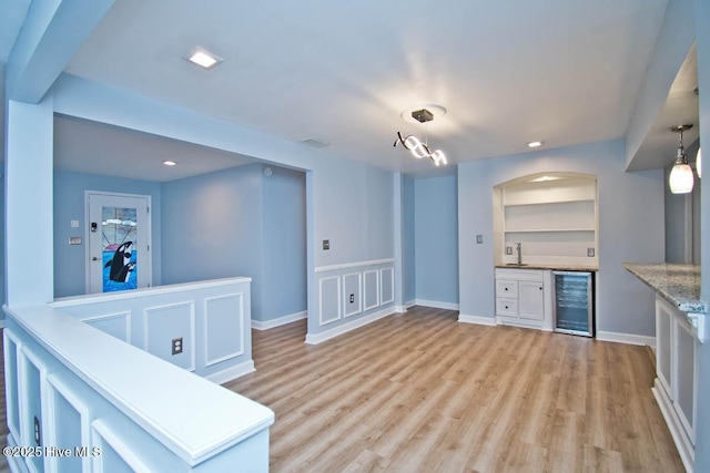 kitchen featuring sink, decorative light fixtures, built in features, white cabinetry, and wine cooler