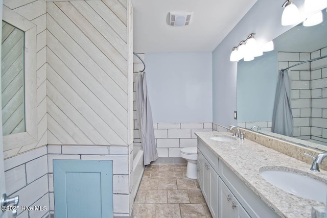 full bathroom with shower / tub combo, vanity, tile walls, and toilet