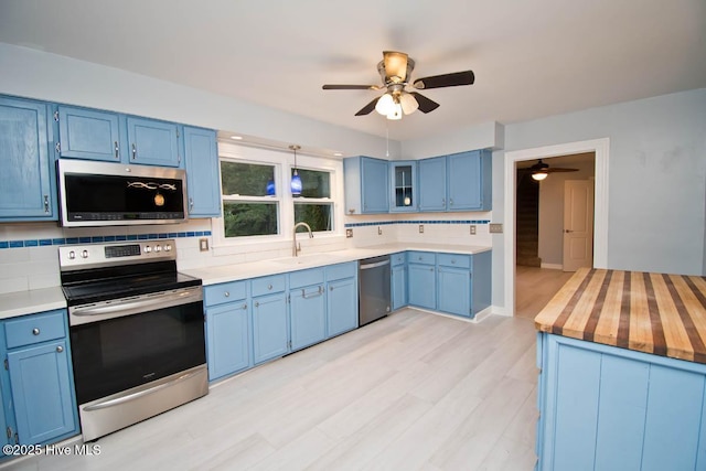 kitchen with blue cabinetry, tasteful backsplash, sink, and stainless steel appliances