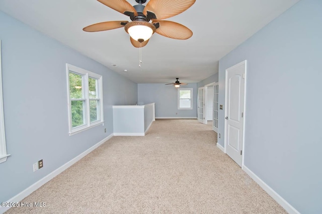 carpeted spare room featuring ceiling fan and plenty of natural light