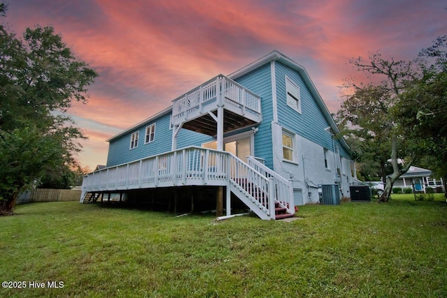 back house at dusk with a lawn, central air condition unit, and a deck