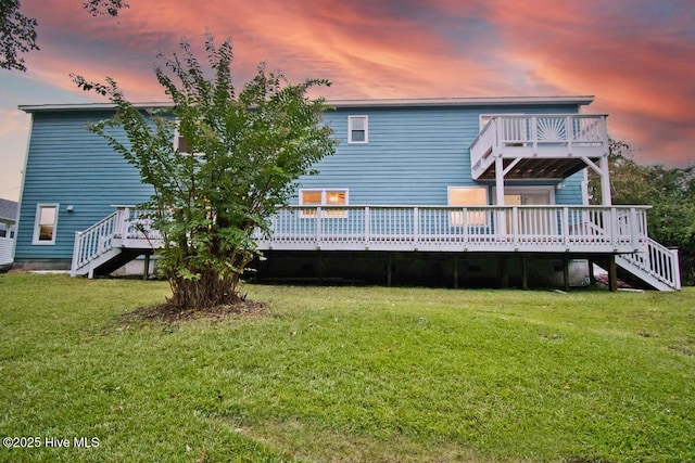 back house at dusk featuring a lawn and a wooden deck