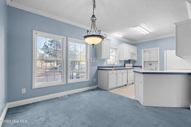 kitchen with light carpet, white appliances, sink, decorative light fixtures, and white cabinets