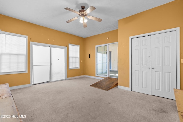 interior space with light carpet, ceiling fan, and multiple closets