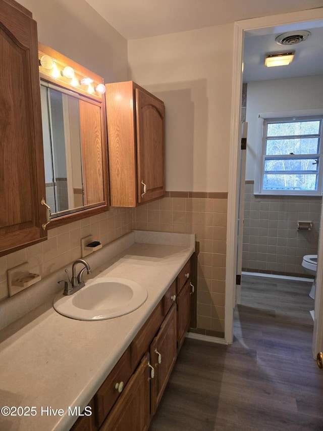 bathroom featuring hardwood / wood-style flooring, vanity, toilet, and tile walls