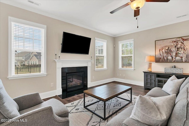 living room with ceiling fan, a healthy amount of sunlight, dark hardwood / wood-style flooring, and ornamental molding