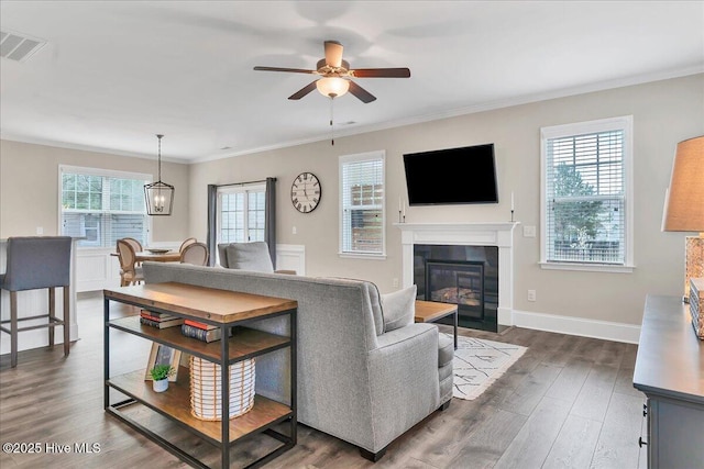 living room featuring a wealth of natural light, ornamental molding, dark hardwood / wood-style floors, and ceiling fan