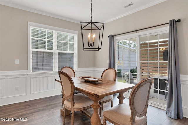 dining room with dark wood-type flooring, an inviting chandelier, and crown molding