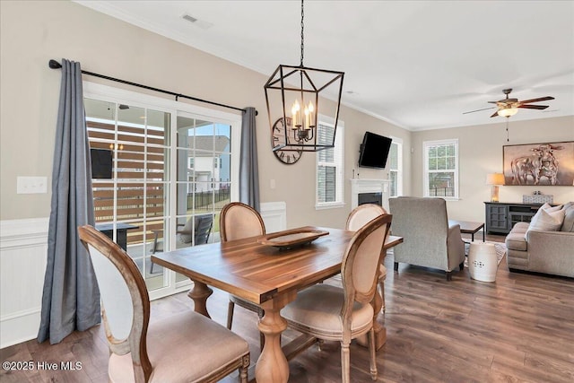 dining room featuring dark wood-type flooring, ceiling fan with notable chandelier, and ornamental molding