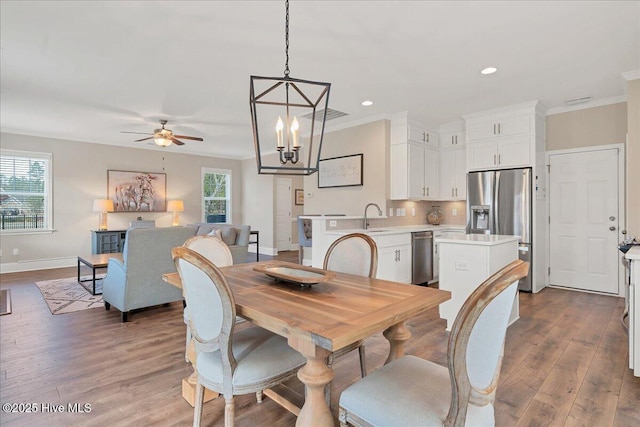 dining area with a wealth of natural light, crown molding, ceiling fan with notable chandelier, and wood-type flooring