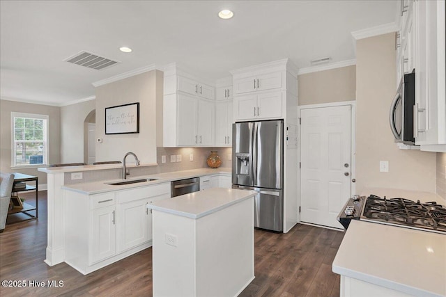 kitchen with a center island, sink, white cabinetry, dark wood-type flooring, and stainless steel appliances