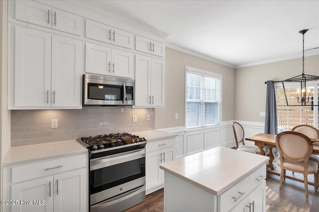 kitchen with backsplash, a notable chandelier, pendant lighting, white cabinetry, and appliances with stainless steel finishes