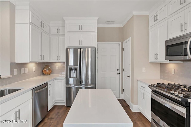 kitchen featuring dark wood-type flooring, stainless steel appliances, white cabinets, and a kitchen island