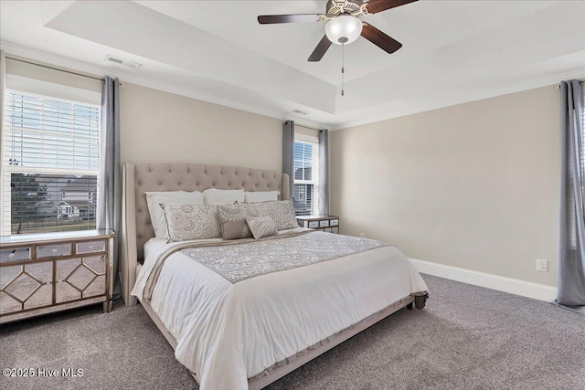 bedroom with a raised ceiling, ceiling fan, and carpet flooring