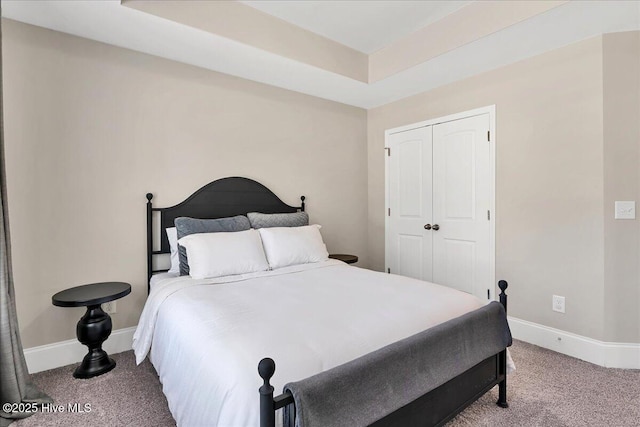 carpeted bedroom with a closet and a tray ceiling