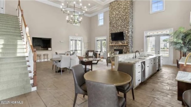 dining room with an inviting chandelier, a fireplace, french doors, a towering ceiling, and sink