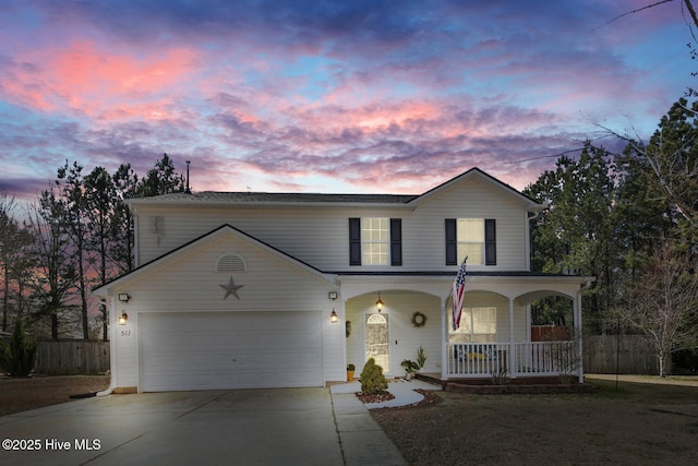 traditional home featuring covered porch, concrete driveway, a garage, and fence