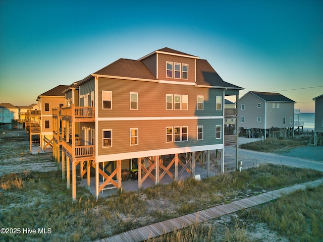 back house at dusk featuring a balcony