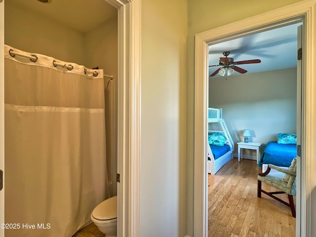 bathroom featuring toilet, ceiling fan, wood-type flooring, and a shower with shower curtain