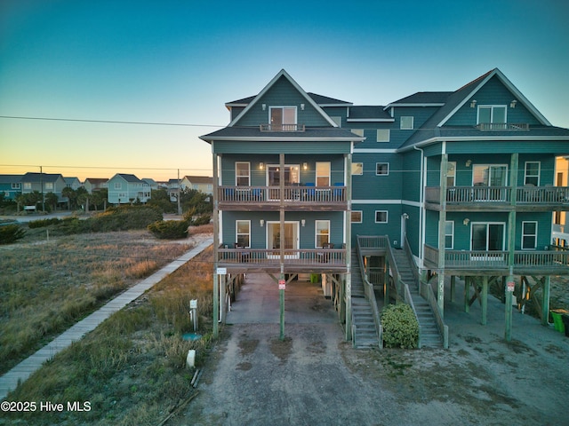 back house at dusk with a carport and a balcony