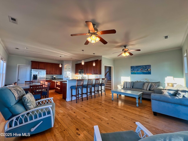 living room featuring ceiling fan, light wood-type flooring, and crown molding