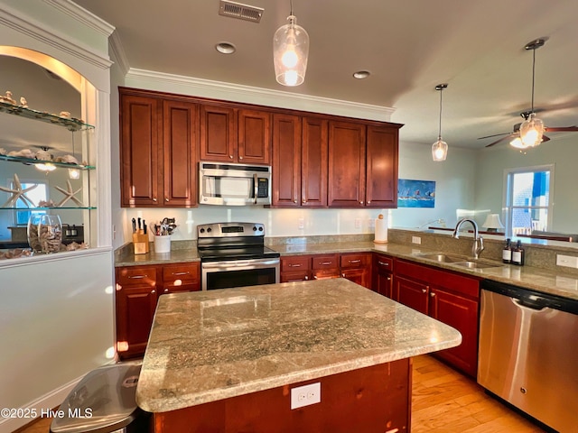 kitchen featuring stainless steel appliances, light stone countertops, pendant lighting, and sink