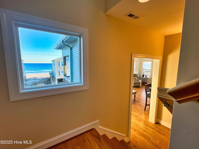 hall with light hardwood / wood-style floors and a water view