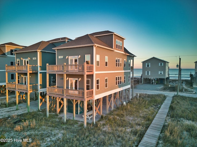 back house at dusk with a balcony and a water view