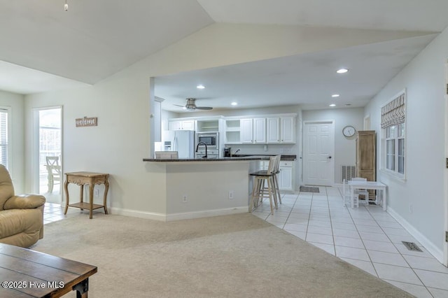 kitchen featuring light carpet, a kitchen bar, kitchen peninsula, white cabinets, and white fridge with ice dispenser