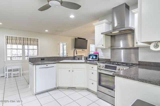 kitchen featuring kitchen peninsula, white cabinets, wall chimney exhaust hood, dishwasher, and stainless steel stove