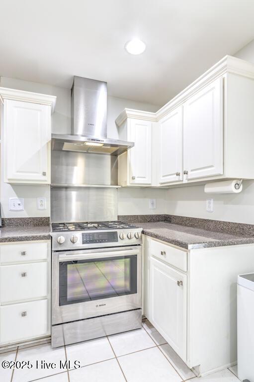 kitchen featuring white cabinets, wall chimney exhaust hood, high end stove, and light tile patterned floors