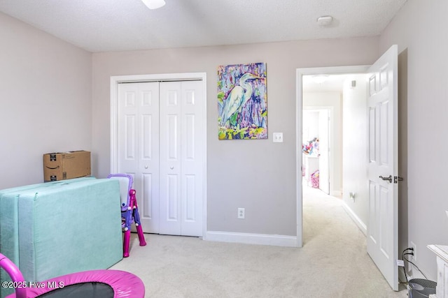 interior space with a textured ceiling, light colored carpet, and a closet