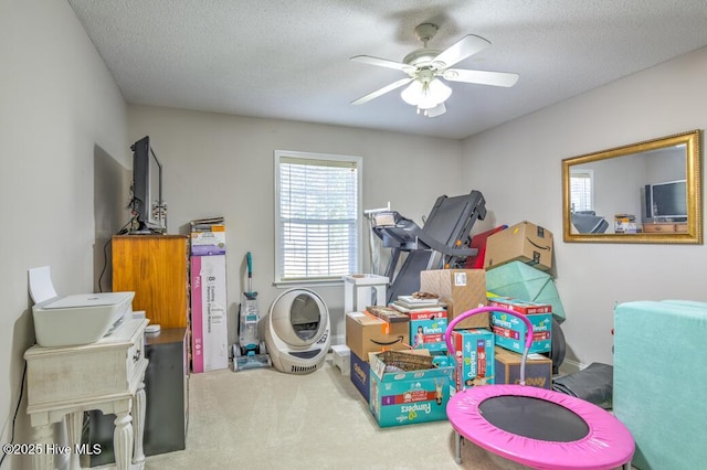 recreation room featuring ceiling fan, carpet, and a textured ceiling