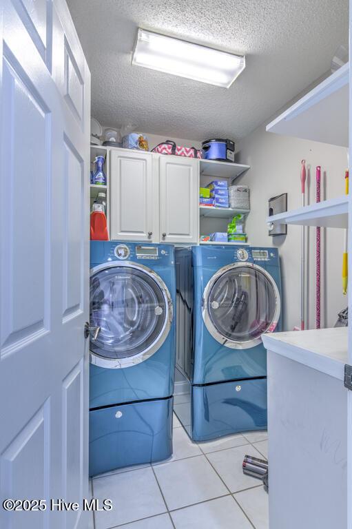 laundry area with cabinets, light tile patterned floors, a textured ceiling, and separate washer and dryer