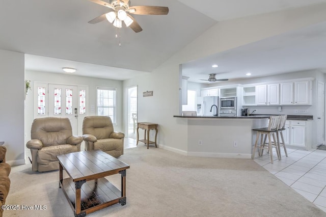 carpeted living room featuring ceiling fan and vaulted ceiling