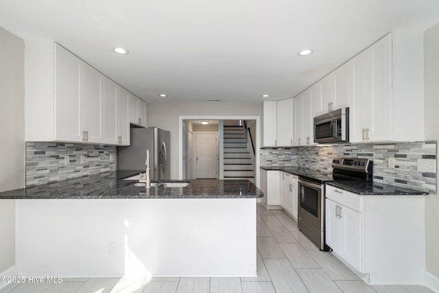 kitchen featuring white cabinetry, appliances with stainless steel finishes, and dark stone countertops