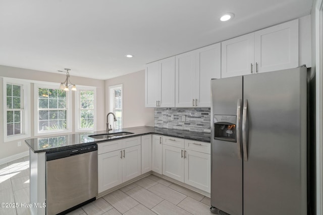 kitchen featuring appliances with stainless steel finishes, white cabinetry, decorative backsplash, sink, and kitchen peninsula