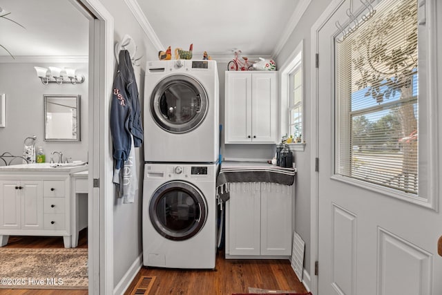 laundry area featuring cabinets, stacked washer and dryer, ornamental molding, dark hardwood / wood-style flooring, and a chandelier