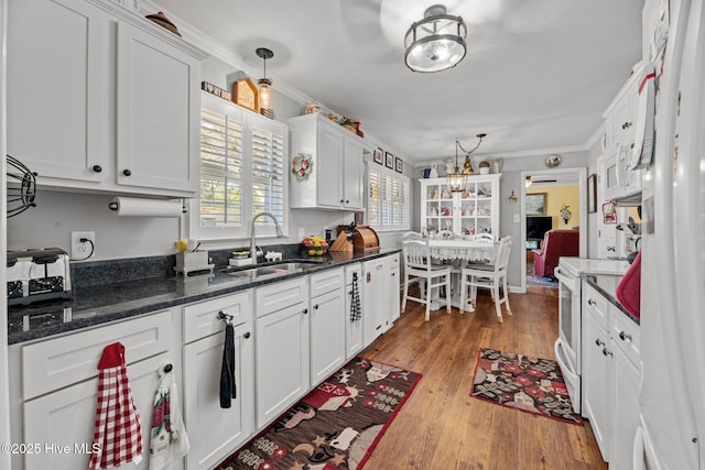 kitchen with white electric range oven, crown molding, sink, pendant lighting, and white cabinets