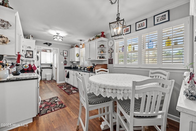 dining room featuring crown molding, sink, and dark wood-type flooring