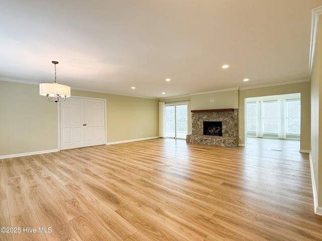 unfurnished living room with light hardwood / wood-style floors, a stone fireplace, crown molding, and a wealth of natural light