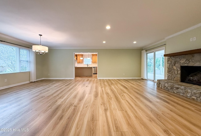 unfurnished living room featuring light wood-type flooring, an inviting chandelier, a stone fireplace, and ornamental molding